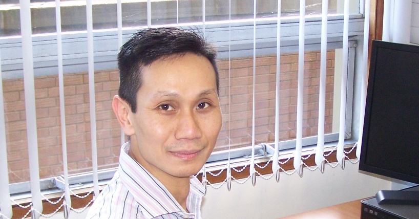 Professor Fai Ng sat at desk, grid size